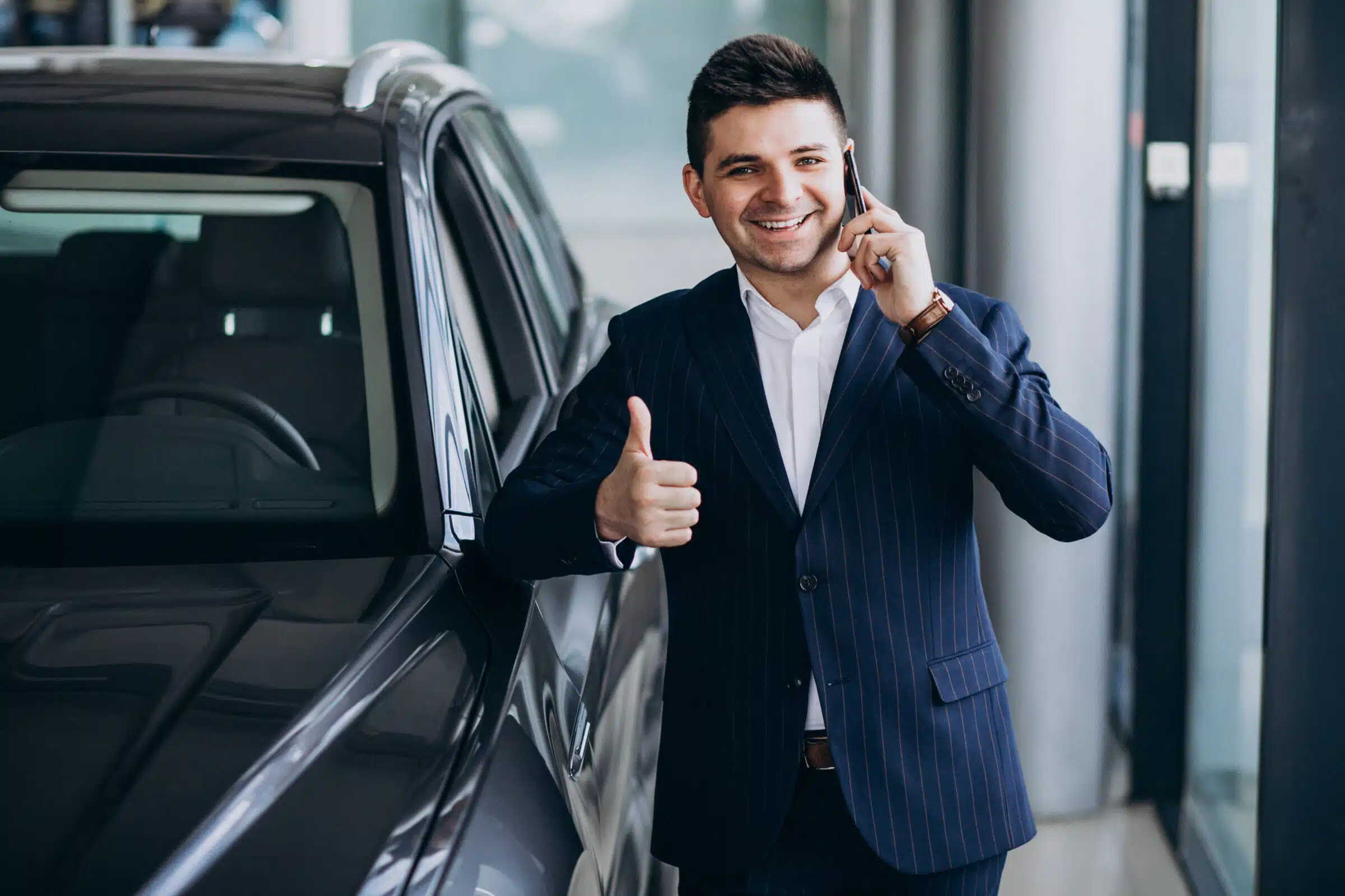 Young handsome business man in a car showroom choosing a car